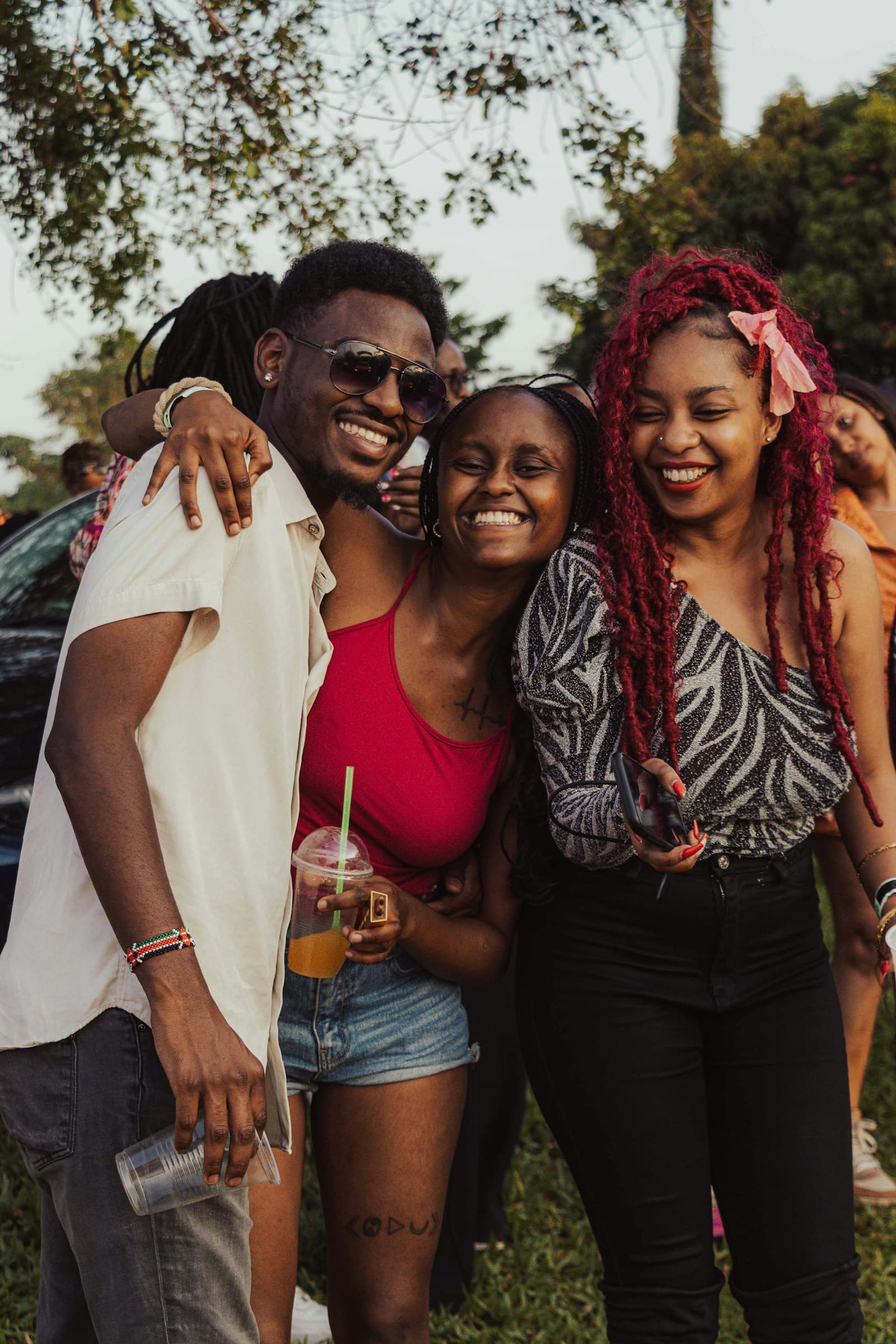 Three friends laughing and hugging at an outdoor gathering