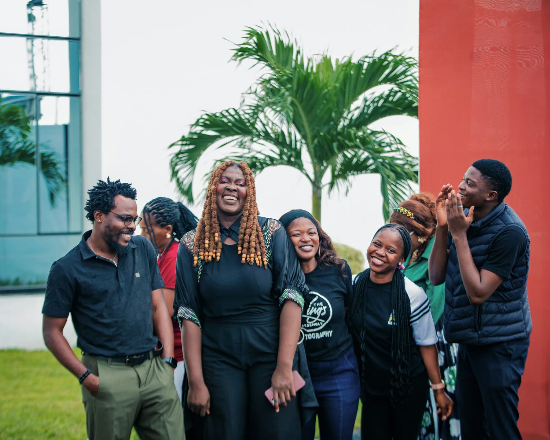 A team of colleagues laughing together outdoors beside a palm tree