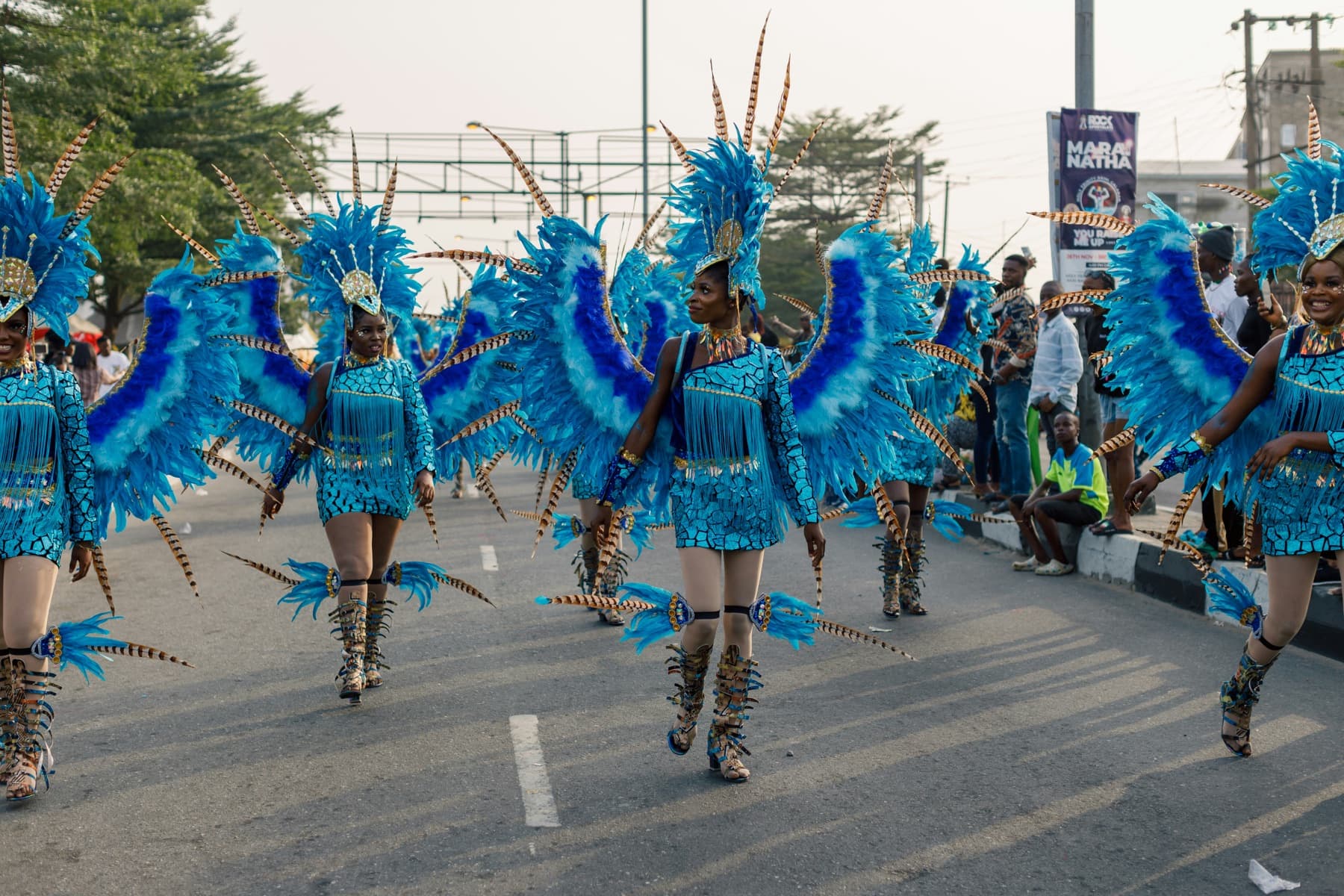 Dancers in blue feathered carnival costumes parading down a street in Nigeria