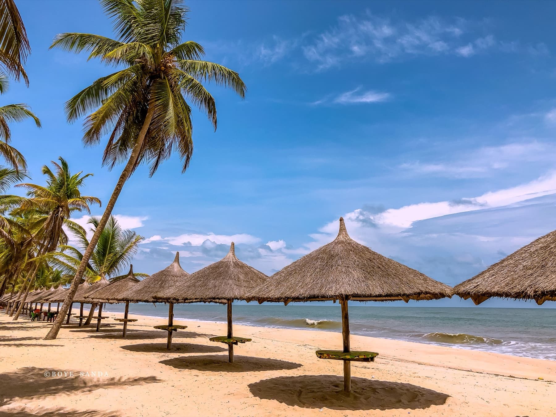 Palm trees and thatched beach umbrellas on a quiet sandy beach in Nigeria